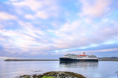 Cruise ship Havila Capella of Havila Kystruten competitor to Hurtigruten in Berlevag harbour, rocks