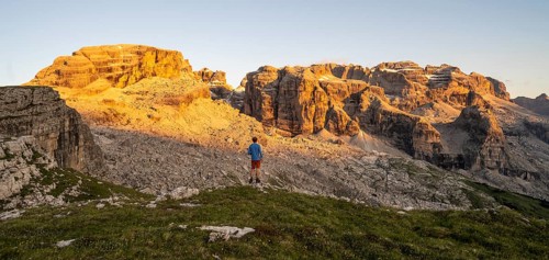 Mountaineer enjoying the view of rocky mountain peaks of the Brenta Mountains at sunset,