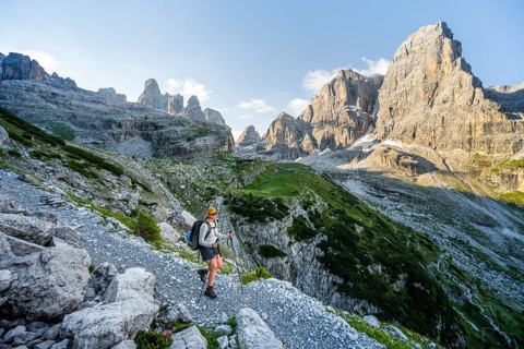 Female mountaineer hiking on a hiking trail in front of picturesque mountain scenery in the