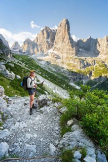 Female mountaineer in front of picturesque mountain landscape in the morning, Cima Tosa rock