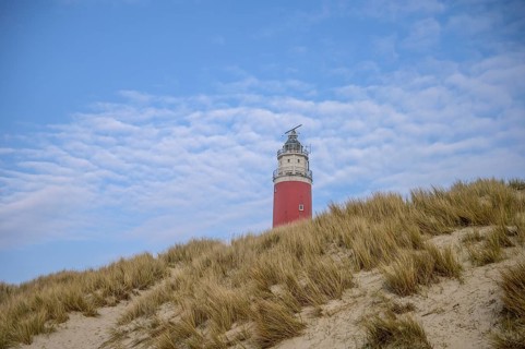 The red lighthouse of De Cocksdorp in the north of the island of Texel rises behind sandy dunes