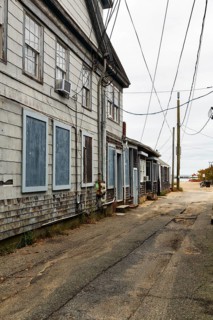 Alley leading to the ocean, weathered timber houses, traditional wood paneling, power lines, former