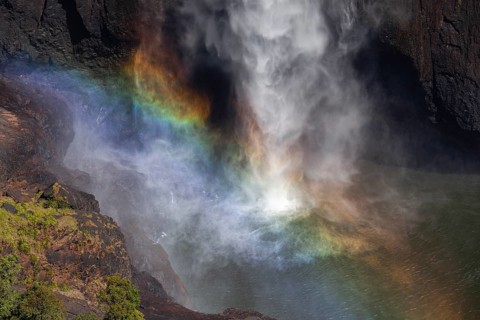 Daytime top view at Wallaman Falls with rainbow in mist over cascading water, Queensland, Australia