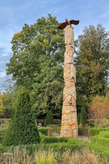 Tree trunk with carvings like a totem pole, stylized eagle on top in front of Schellenberg hunting