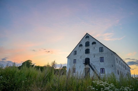 A historic stone building under a colorful evening sky at sunset, old merchant magazine, Südpunkt