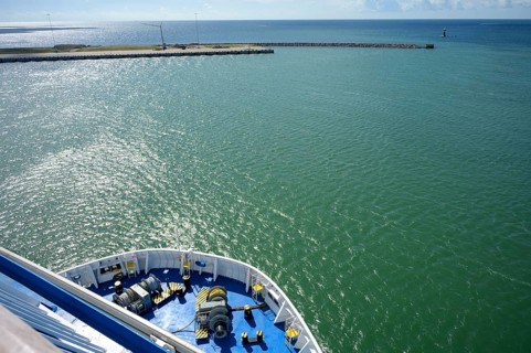 Front view of a TT-Line ferry leaving the port exit under a blue sky with a clear horizon,