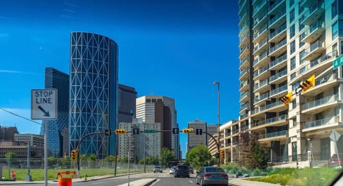 Cars driving on a multi lane road with the bow skyscraper and other modern buildings along the