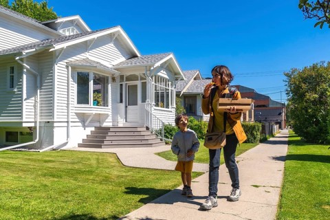 Mother and son are walking down a sidewalk in a residential neighborhood in calgary, alberta,