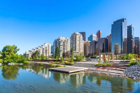 Modern buildings of downtown calgary reflecting in the calm water of a pond in st. Patrick's island
