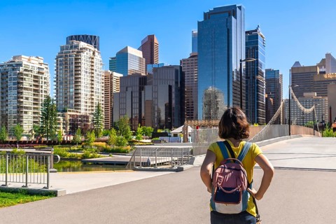 Young female tourist with a backpack is enjoying the cityscape of calgary, alberta, canada,