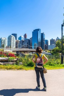 Tourist with a backpack stands in a colorful park, gazing at the modern cityscape of calgary,
