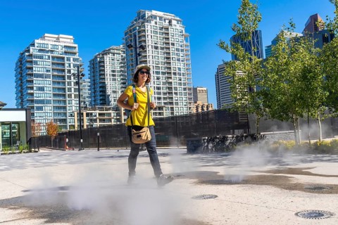 Female tourist walking in a foggy square in calgary city center during a sunny summer day, enjoying