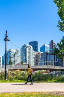 Young woman tourist walking in a city park in calgary, canada, enjoying the summer weather and