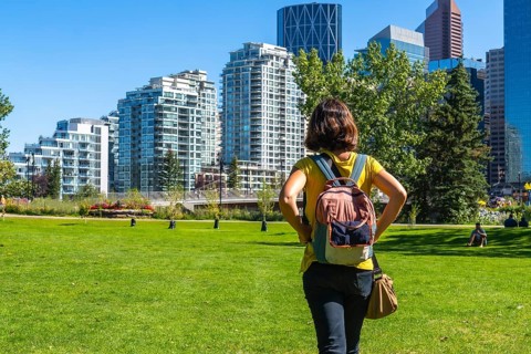 Female tourist with a backpack enjoying a sunny day in calgary's park, taking in the stunning views