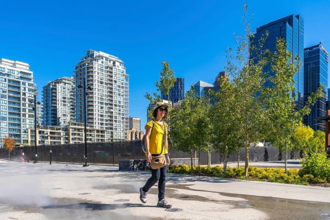 Tourist wearing a yellow t shirt and a hat is enjoying a walk in calgary's east village