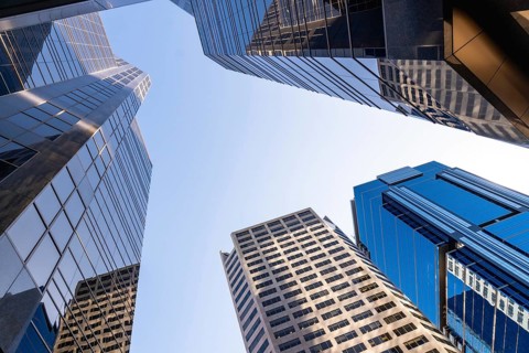 Low angle view of modern skyscrapers towering against a clear blue sky in calgary, alberta,