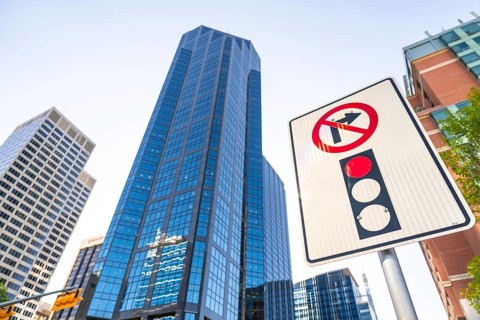 Low angle view of a no right turn sign and traffic light against towering modern skyscrapers in