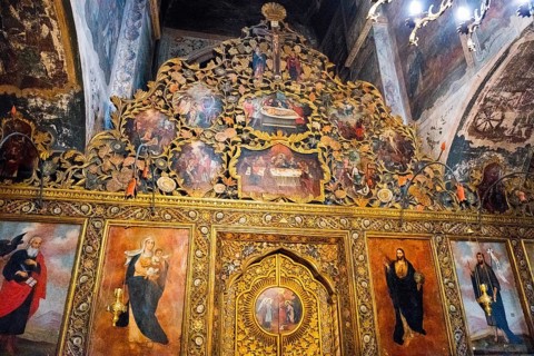 Artistically decorated icon wall with golden elements and religious representations in a church,