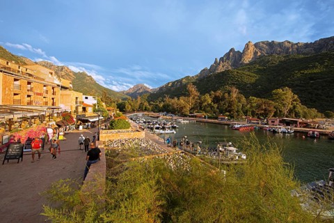 Boats in Port de Porto or Port on the Porto River, Capu d'Orto Mountains in the back, afternoon