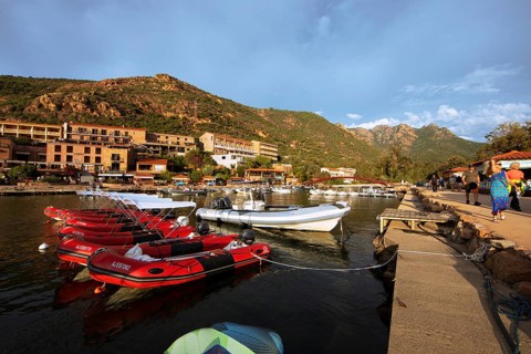 Colourful boats in Port de Porto or Port on the Porto River, in the background the Capu d'Orto