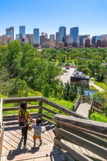 Mother and son descending a wooden staircase in a park, enjoying a picturesque view of the calgary