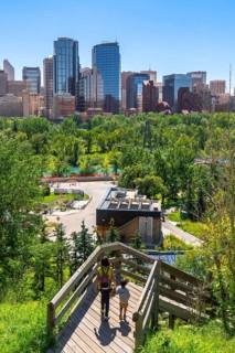 Mother and son descending wooden stairs, enjoying the vibrant urban park with the stunning calgary