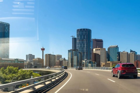 Cars driving along a highway showcase the vibrant calgary skyline, featuring the iconic calgary