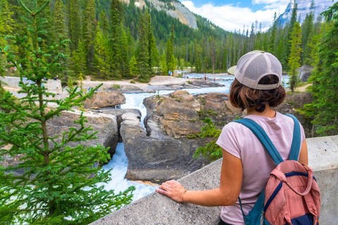 Female tourist with backpack enjoying the breathtaking view of the bow river natural bridge, a