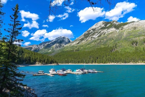 Many motorboats are resting on the turquoise waters of lake minnewanka, surrounded by the imposing