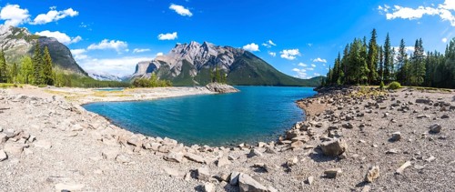 Turquoise waters of lake minnewanka reflecting surrounding mountains and forests in banff national