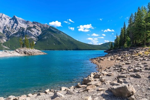 Breathtaking turquoise water of lake minnewanka reflecting the majestic canadian rockies under a