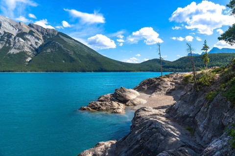 Breathtaking turquoise waters of lake minnewanka reflecting the majestic canadian rockies under a