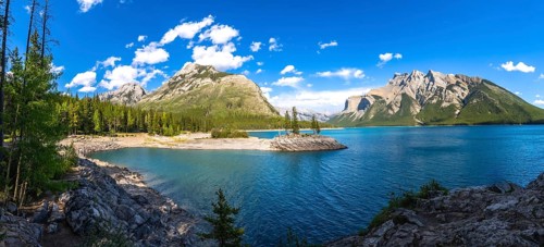 Sunlight illuminating the turquoise waters of lake minnewanka, reflecting surrounding mountains and