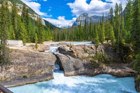 Turquoise water of bow river flowing underneath the natural bridge rock formation on a sunny summer