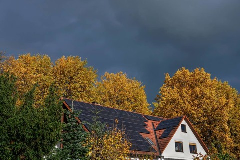Stormy atmosphere with autumn trees and house with photovoltaic on the roof, Eckental, Middle