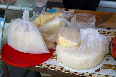 Different types of cheese in plastic packaging on a table at a market stall, selling cheese,