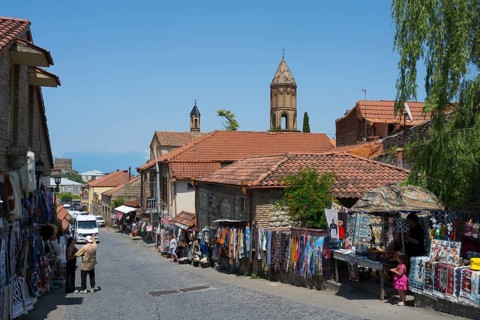 A lively market street in a village with people buying souvenirs at colorful stalls, Old Town,