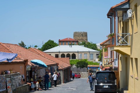 Urban street scene with people, red roofs and castle in the background, old town, Sighnaghi,