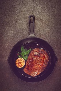 Grilled rib eye steak, in a cast-iron skillet, top view, homemade, no people