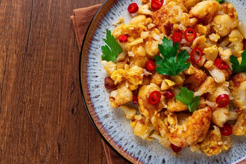 Spicy fried cauliflower served on a wooden countertop