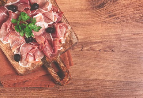 Sliced prosciutto, on a cutting board, with olives and herbs, snack, breakfast, no people