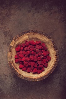 Fresh raspberries in a wooden bowl, food background, concept, food styling, on a dark table, top