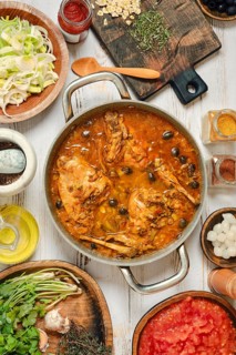 A large pot holds a simmering stew made with rabbit meat, vegetables, and a variety of spices.
