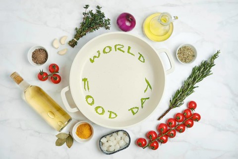 Fresh vegetables, herbs, white wine and cooking oil are arranged on a kitchen countertop next to an