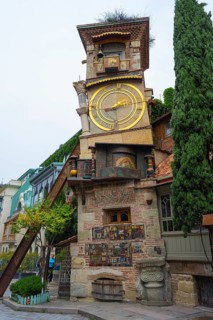 An old building with a big clock in a charming architectural style, surrounded by trees, clock
