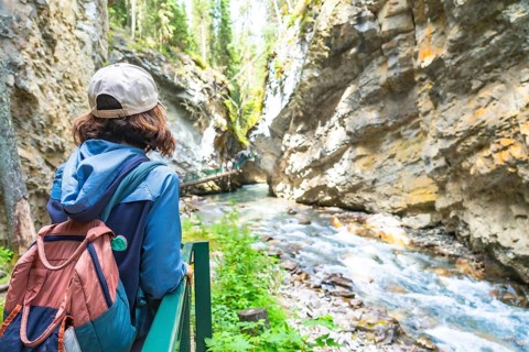 Female tourist with a backpack admiring the breathtaking turquoise waters flowing through the rocky