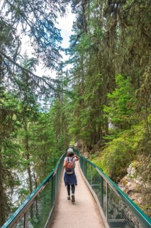 Female tourist walking on johnston canyon boardwalk enjoying breathtaking views of the bow river