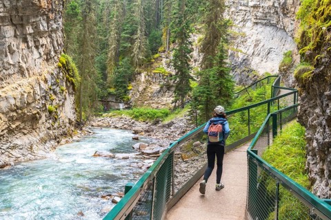 Female tourist with a backpack walking along a metal catwalk, taking in the scenic views of