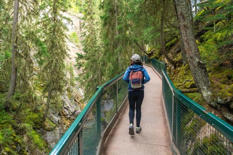 Female tourist with backpack walking on the johnston canyon catwalk trail in banff national park,