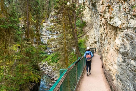 Female hiker walking the johnston canyon catwalk trail, enjoying the scenic beauty of the canyon,